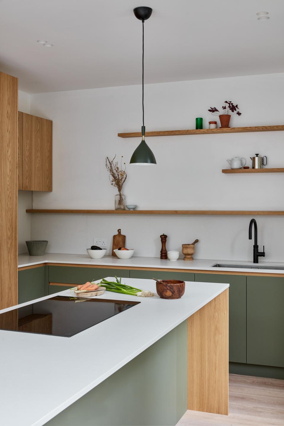 Modern kitchen with green cabinetry, natural wood accents, and stylish decor, showcasing a connection to nature in design.