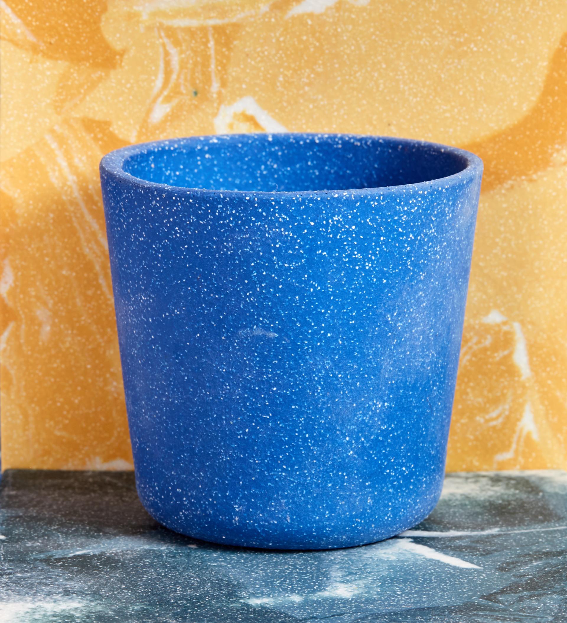 Bright blue encaustic ceramic pot against a textured yellow and marbled green backdrop, highlighting Granby Workshop's artistic design.