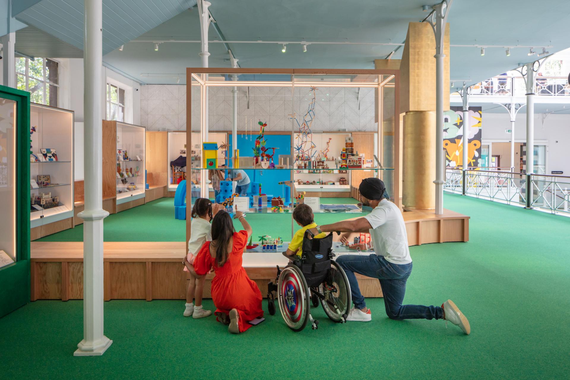 Children and a caregiver explore interactive exhibits in the vibrant, child-friendly environment of Young V&A museum.