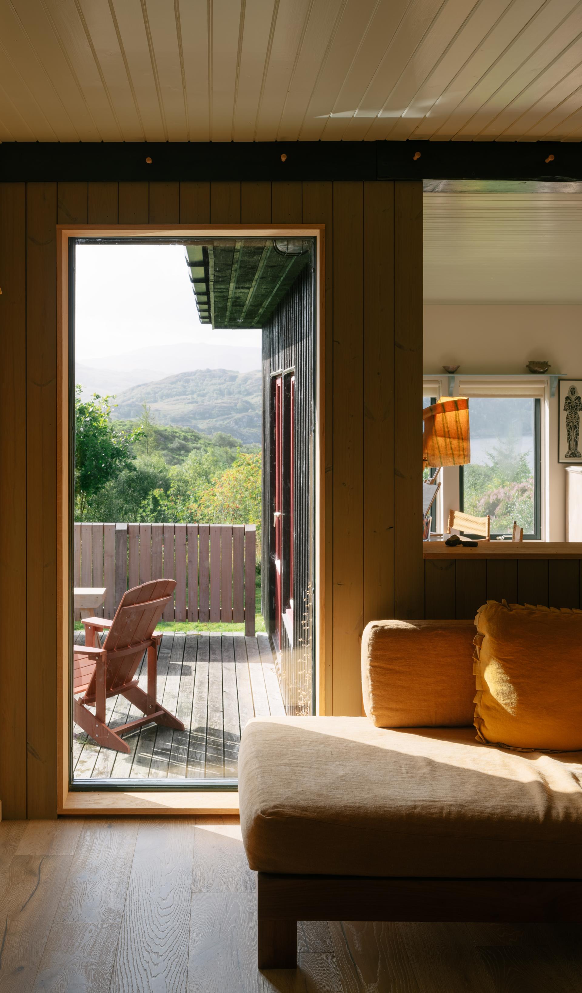 Cozy interior showcasing Hebridean design elements with a view of Scandinavian-inspired architecture and surrounding hills.