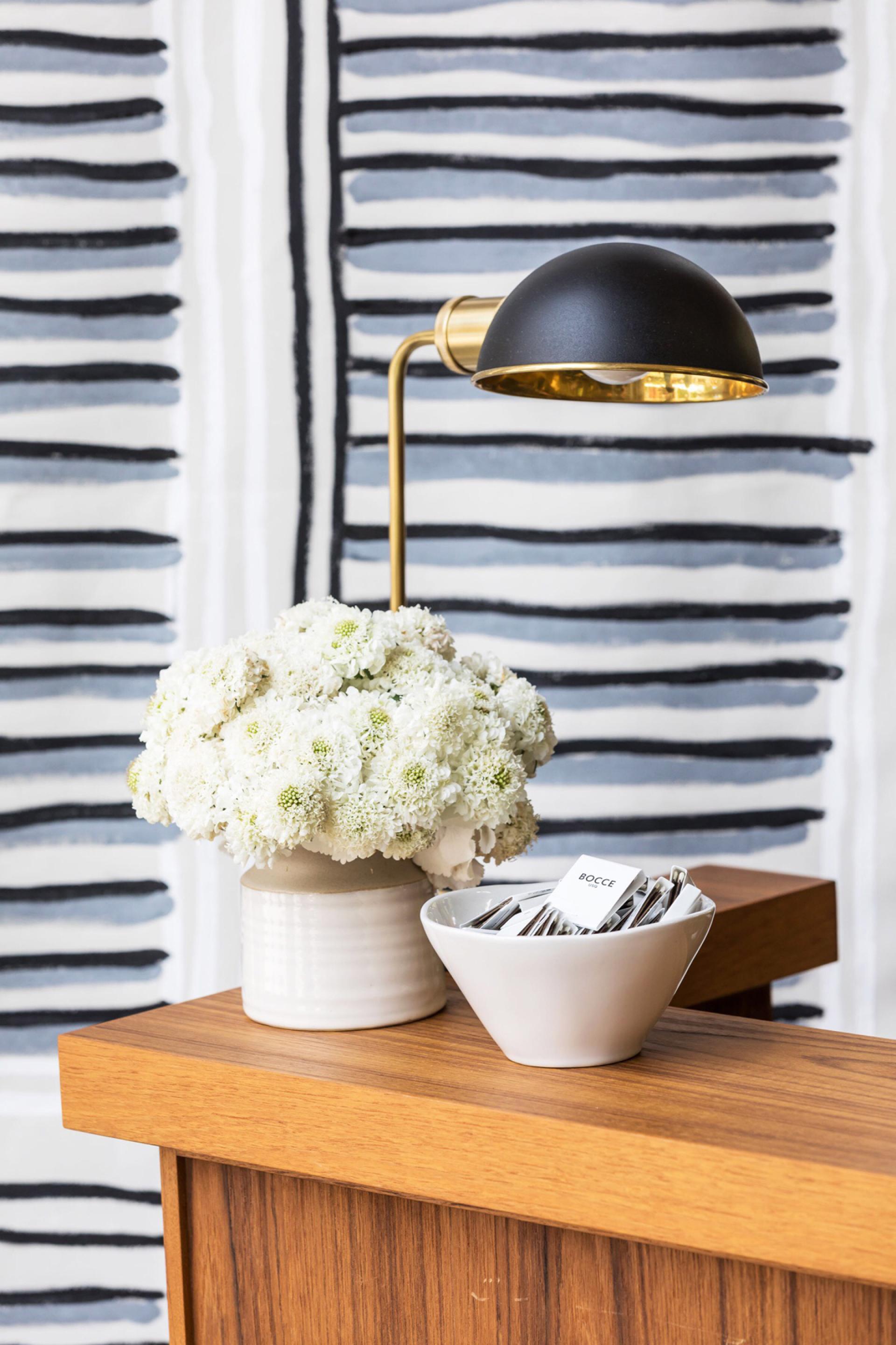 Stylish table setting at Bocce featuring white floral arrangement, modern lamp, and a bowl with name cards.