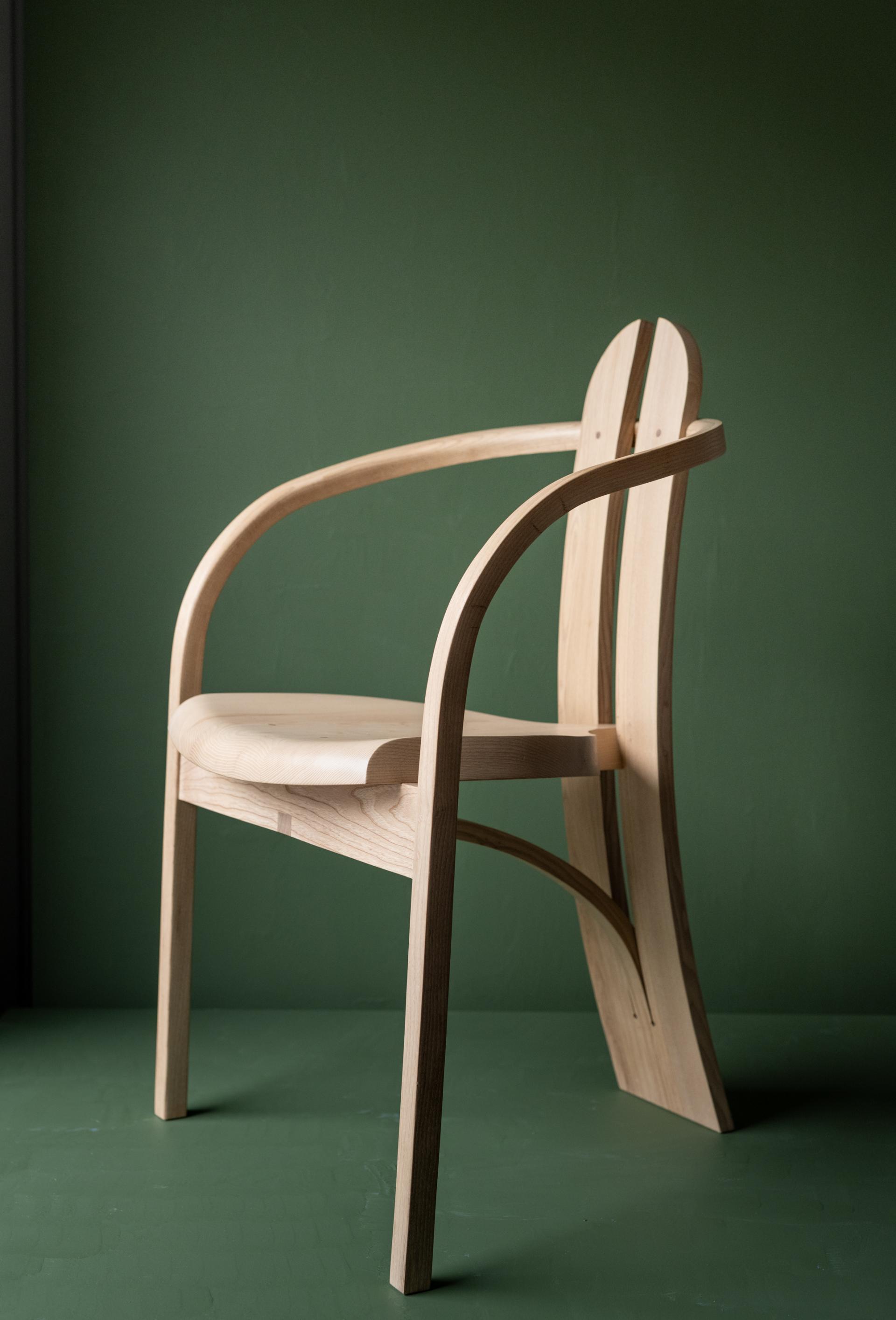 Elegant ash wood chair showcasing craftsmanship and material intelligence, set against a green background.