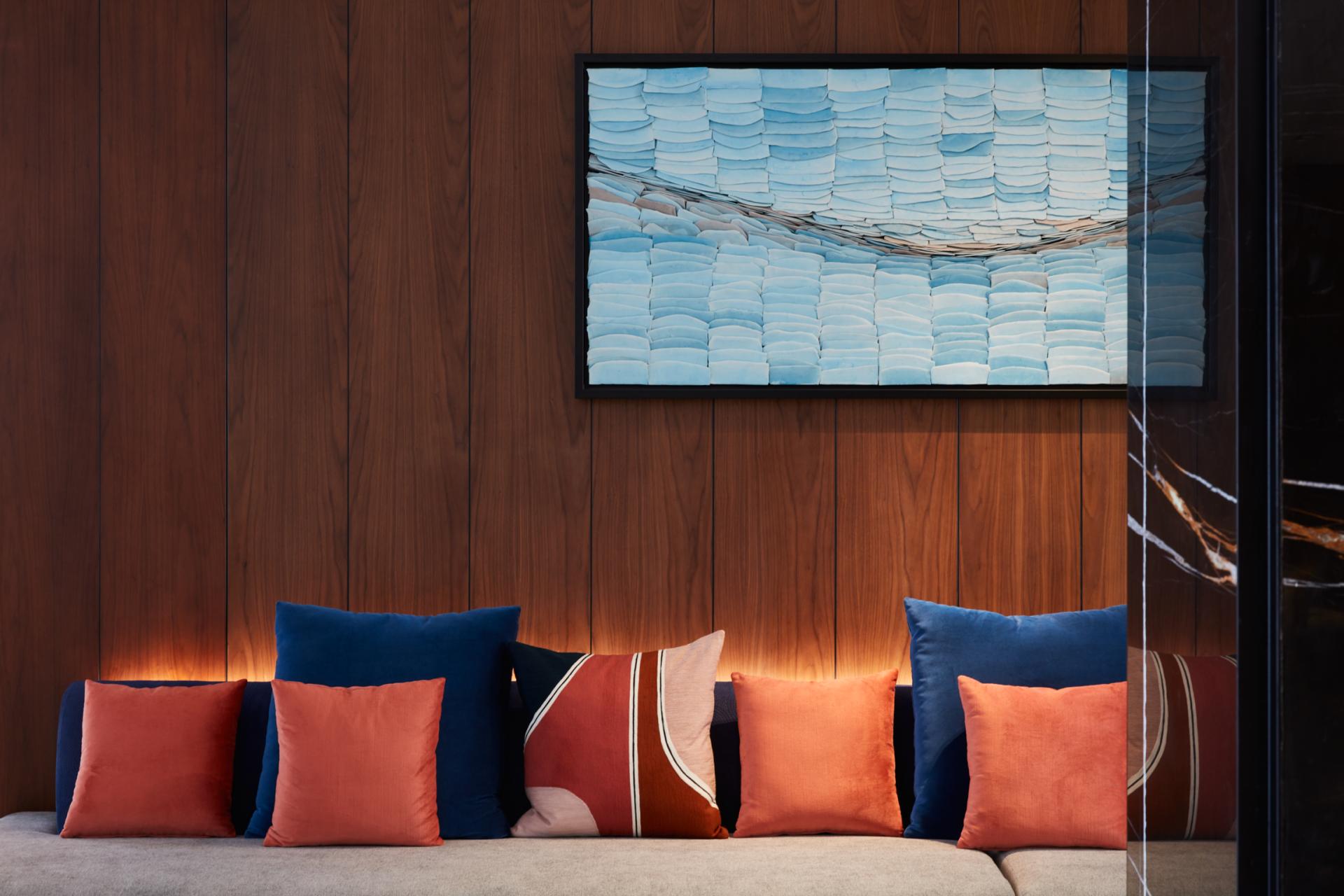 Contemporary lounge area in The8 Hotel, featuring vibrant cushions and a blue-toned artwork, blending art and design.