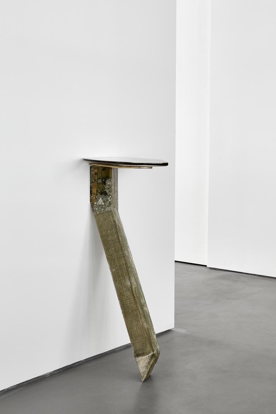 Sculptural furniture piece with a textured metallic leg and a sleek tabletop, featured in Vincenzo de Cotiis exhibition.