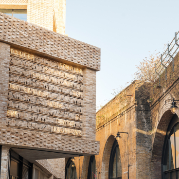 Modern architecture at Borough Yards features textured brick exterior with illuminated signage, highlighting a cultural destination in London.