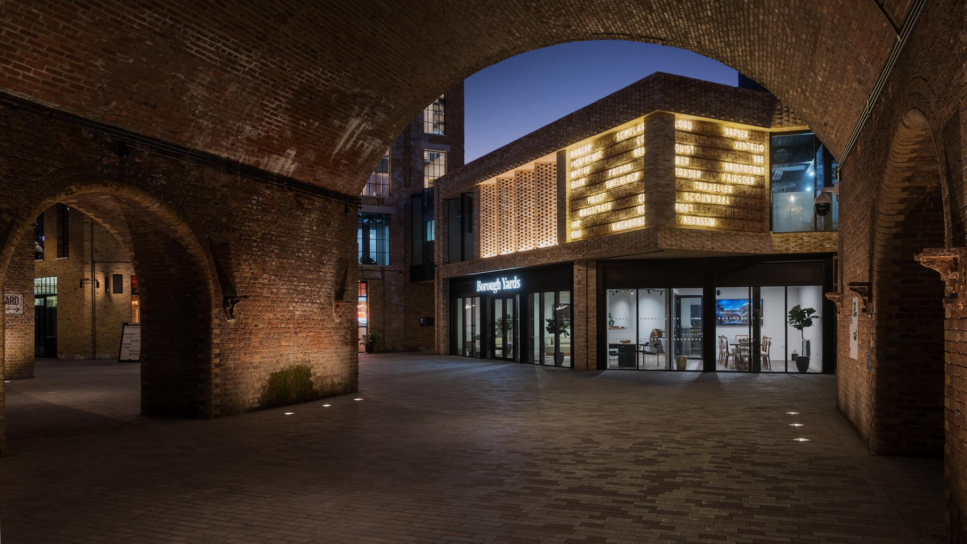 Borough Yards' vibrant night scene showcases modern architecture blending with medieval brick arches in London.