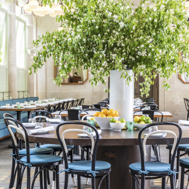 Modern dining space at Bocce, featuring a large floral centerpiece and wooden tables, reflecting Gachot Studios' design aesthetic.