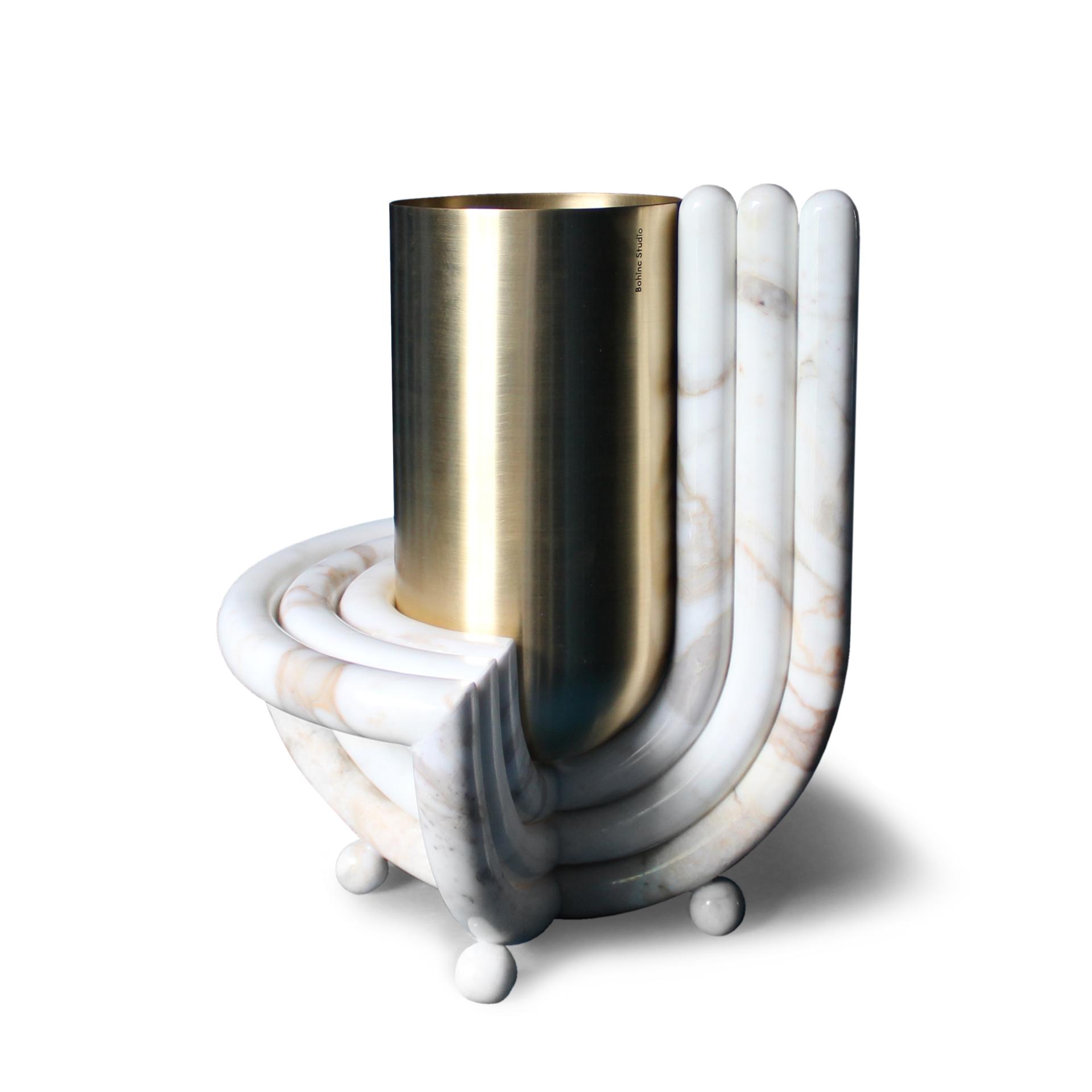 Sculptural vase design featuring a cylindrical brass element atop a curved marble base, showcasing modern elegance and craftsmanship.