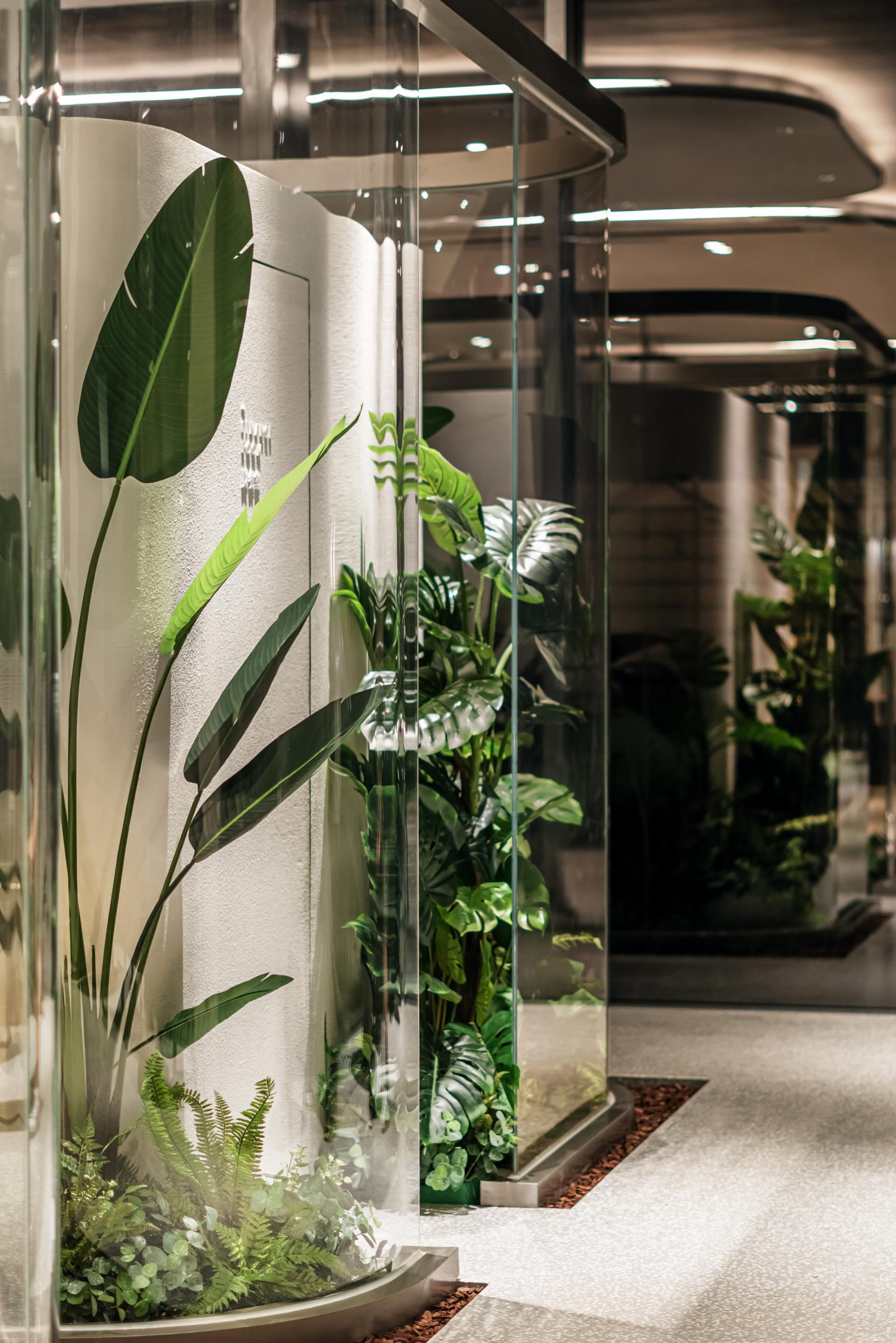 Modern glass corridor adorned with lush green plants, showcasing a nature-inspired design in a multi-media restaurant.