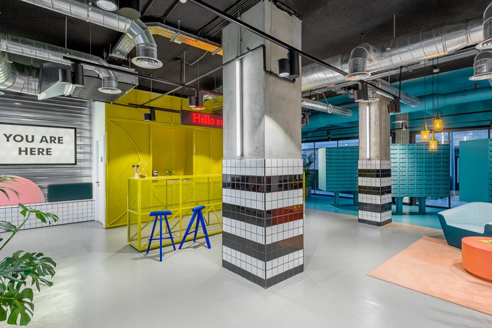 Vibrant co-working space at The Student Hotel Barcelona featuring colorful decor, a reception area, and inviting seating.