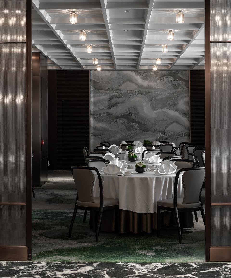 Elegant Canton Room interior featuring round tables with white linens, greenery, and modern decor, overlooking Victoria Harbour.