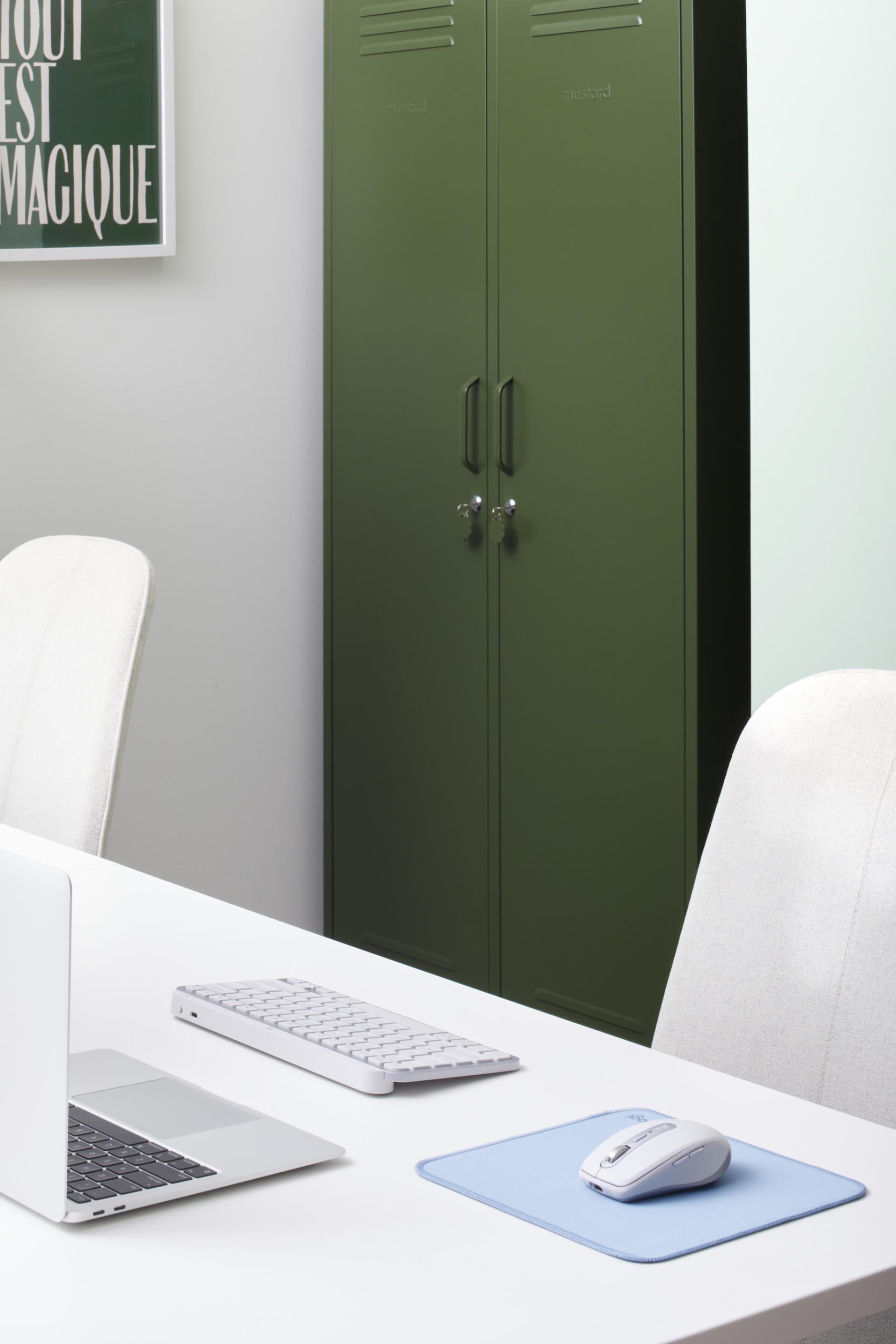 Stylish workspace featuring Mustard Made green lockers, a laptop, keyboard, and mouse on a clean desk.