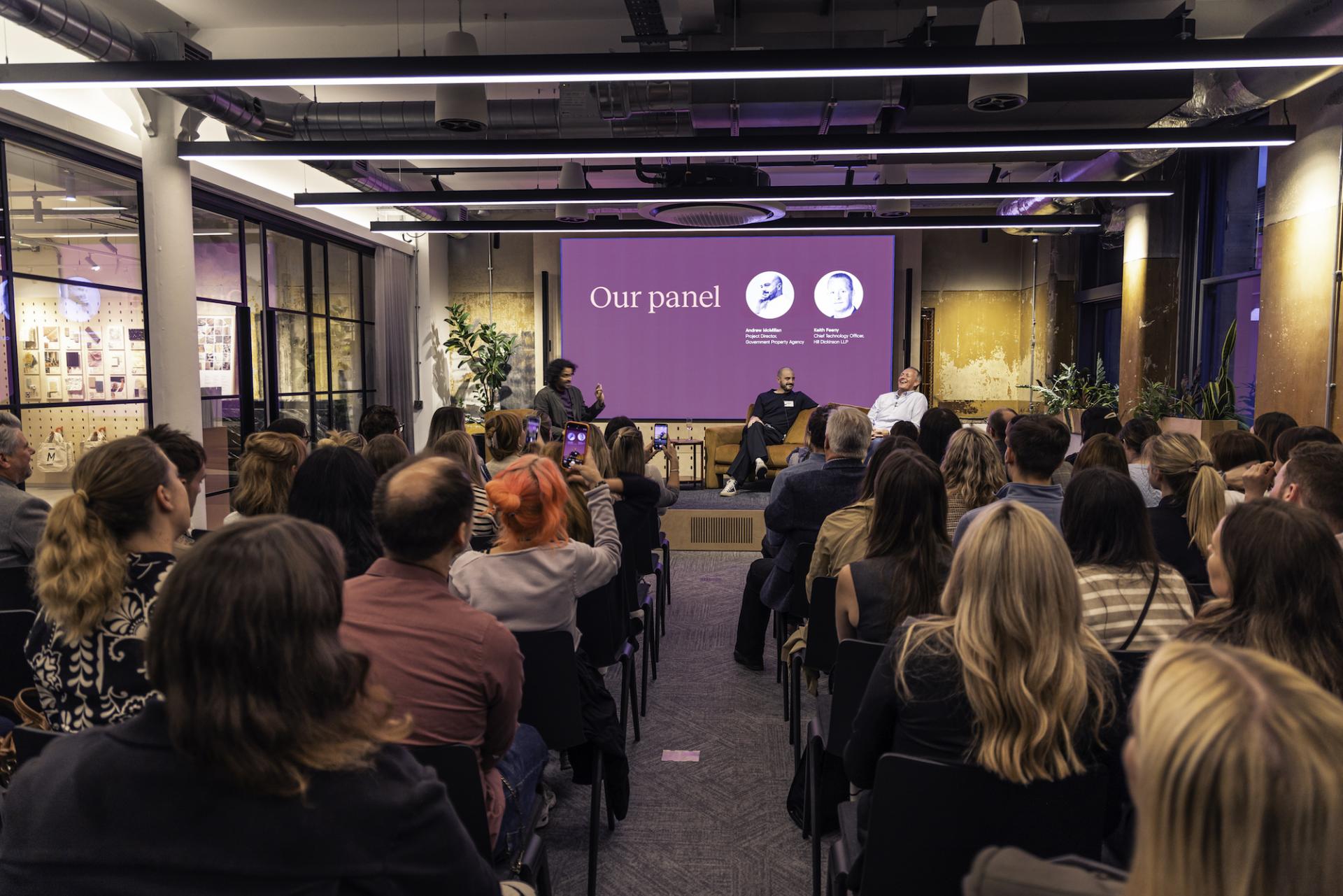 Panel discussion on technology in the workplace, featuring speakers engaged with an audience in a modern venue.