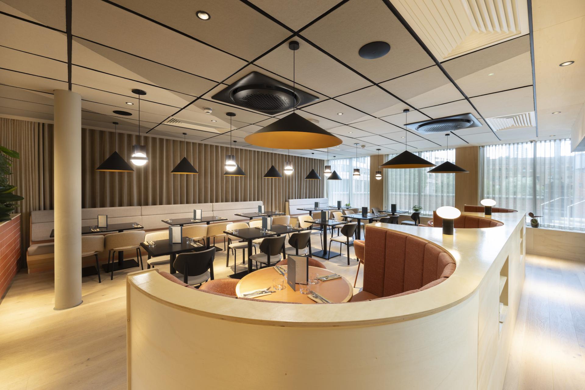 Stylish modern restaurant interior featuring wooden accents, diverse seating arrangements, and large windows for natural light.