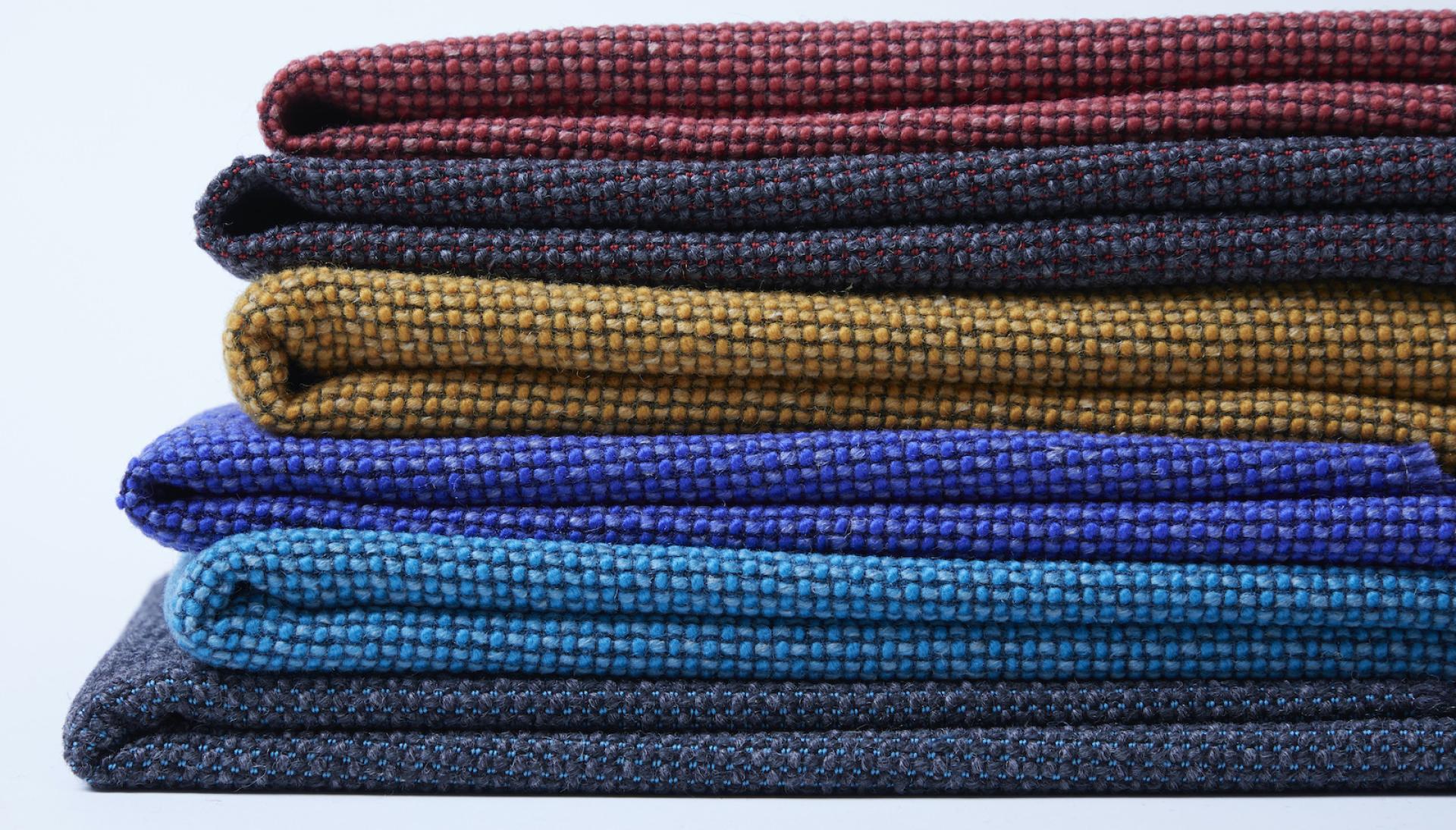 Textured fabric swatches in various colors showcasing Camira's sustainable Craggan Flax textiles, highlighting eco-friendly design.