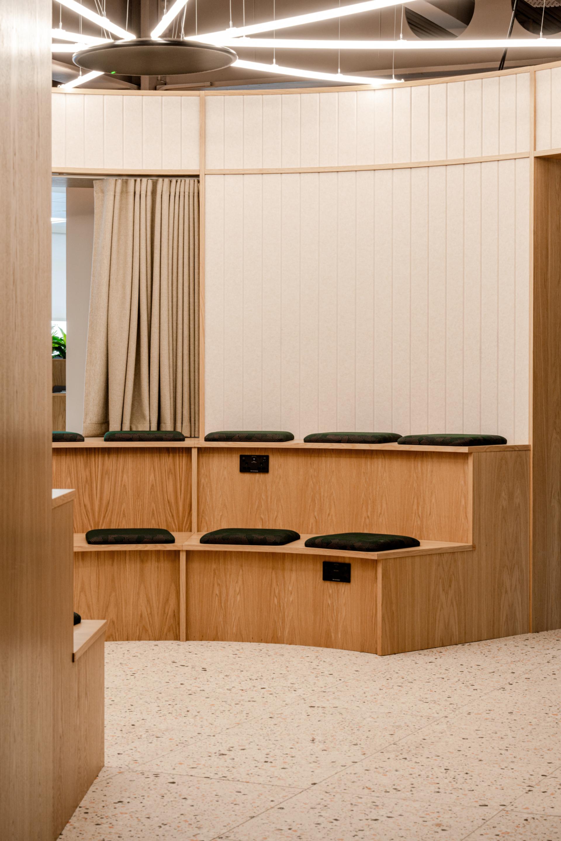 Modern workspace interior featuring wooden seating with cushions, emphasizing Scotland's craftsmanship and innovative design elements.