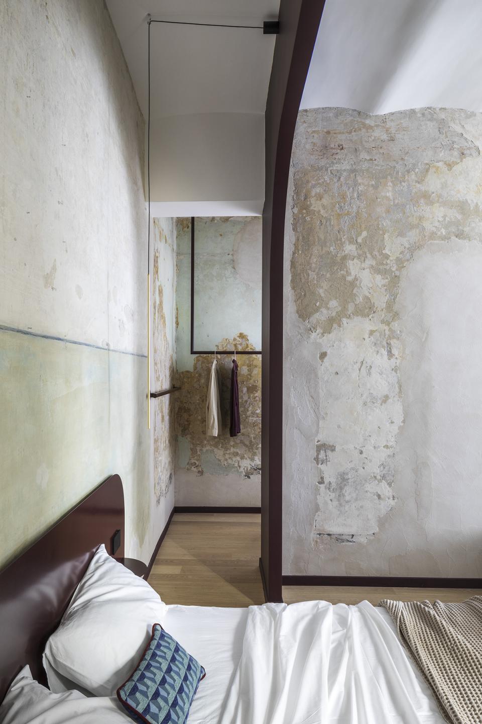 Stylish interior of a Trastevere apartment featuring unique textured walls, cozy bedding, and minimalistic design elements.