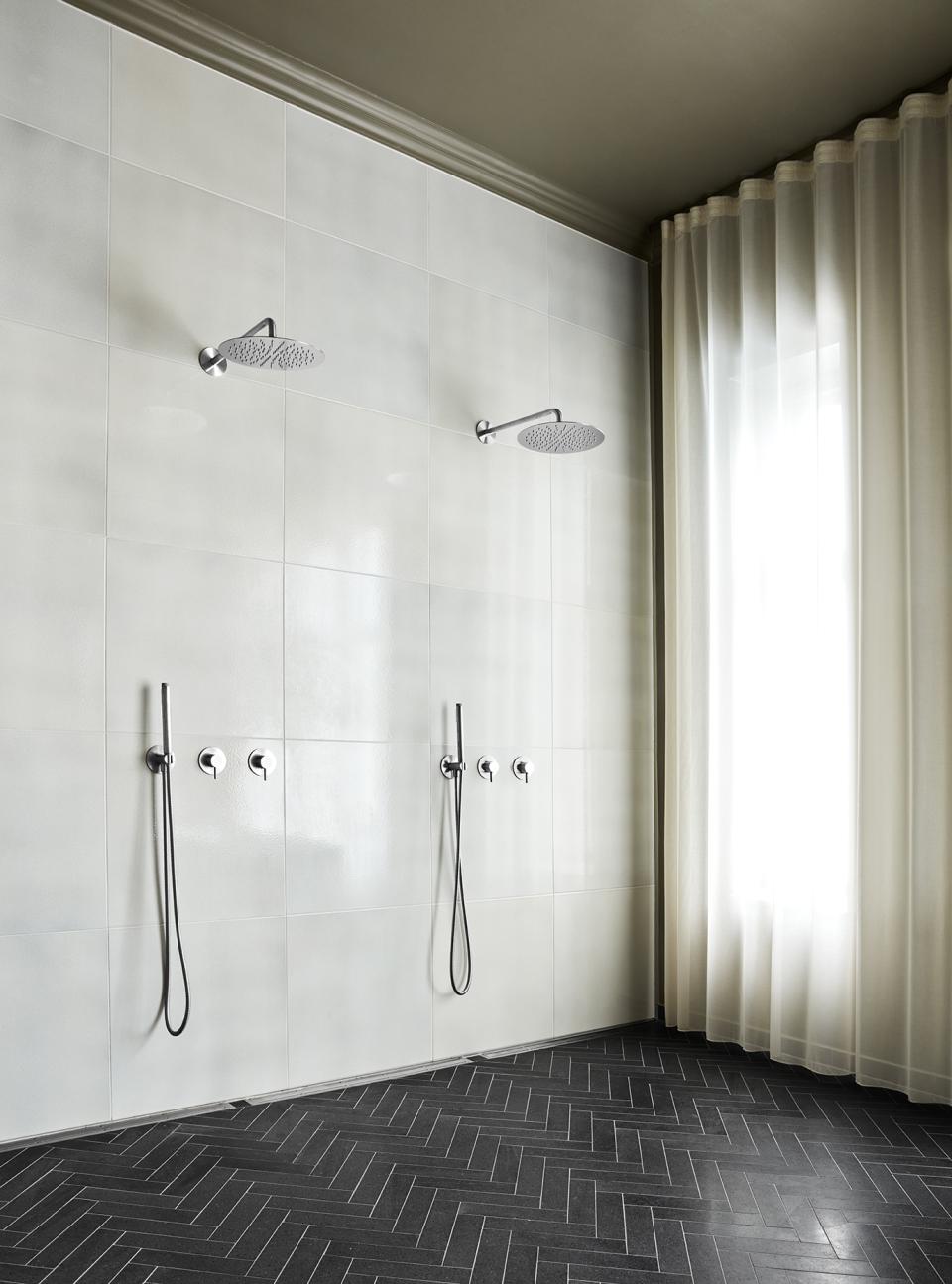 Elegant bathroom featuring d line's Qtoo collection shower fixtures, soft curtains, and herringbone tiled flooring in Østerbro.