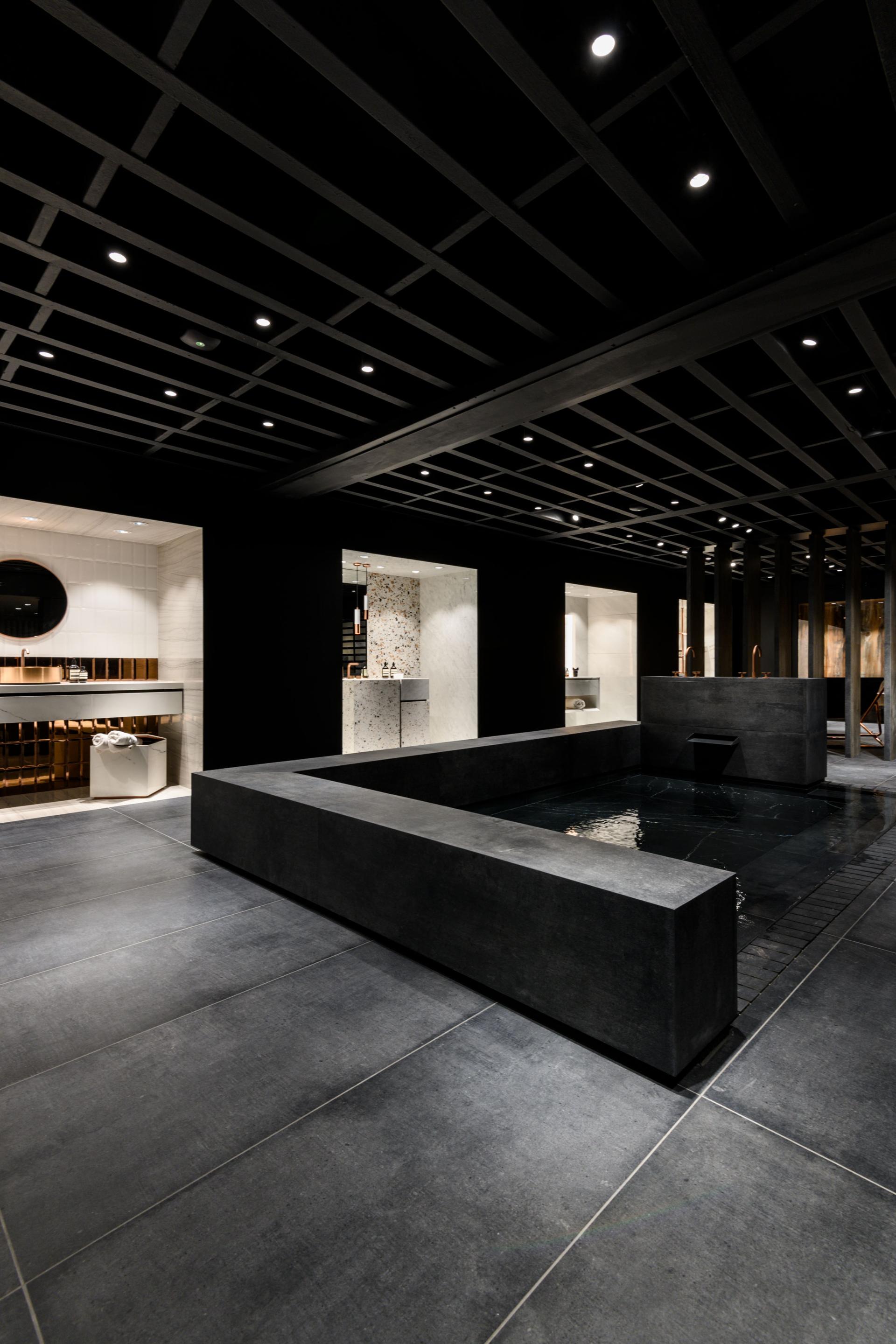 Contemporary showroom featuring elegant stone surfaces and a water feature, showcasing Iris Ceramica Group's design expertise.