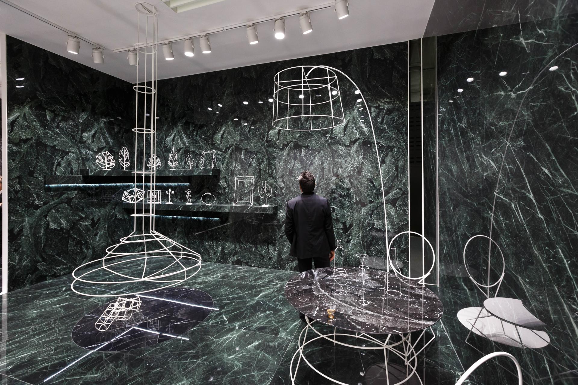 Innovative interior design display featuring geometric furniture against a striking green marble backdrop at CERSAIE 2019.