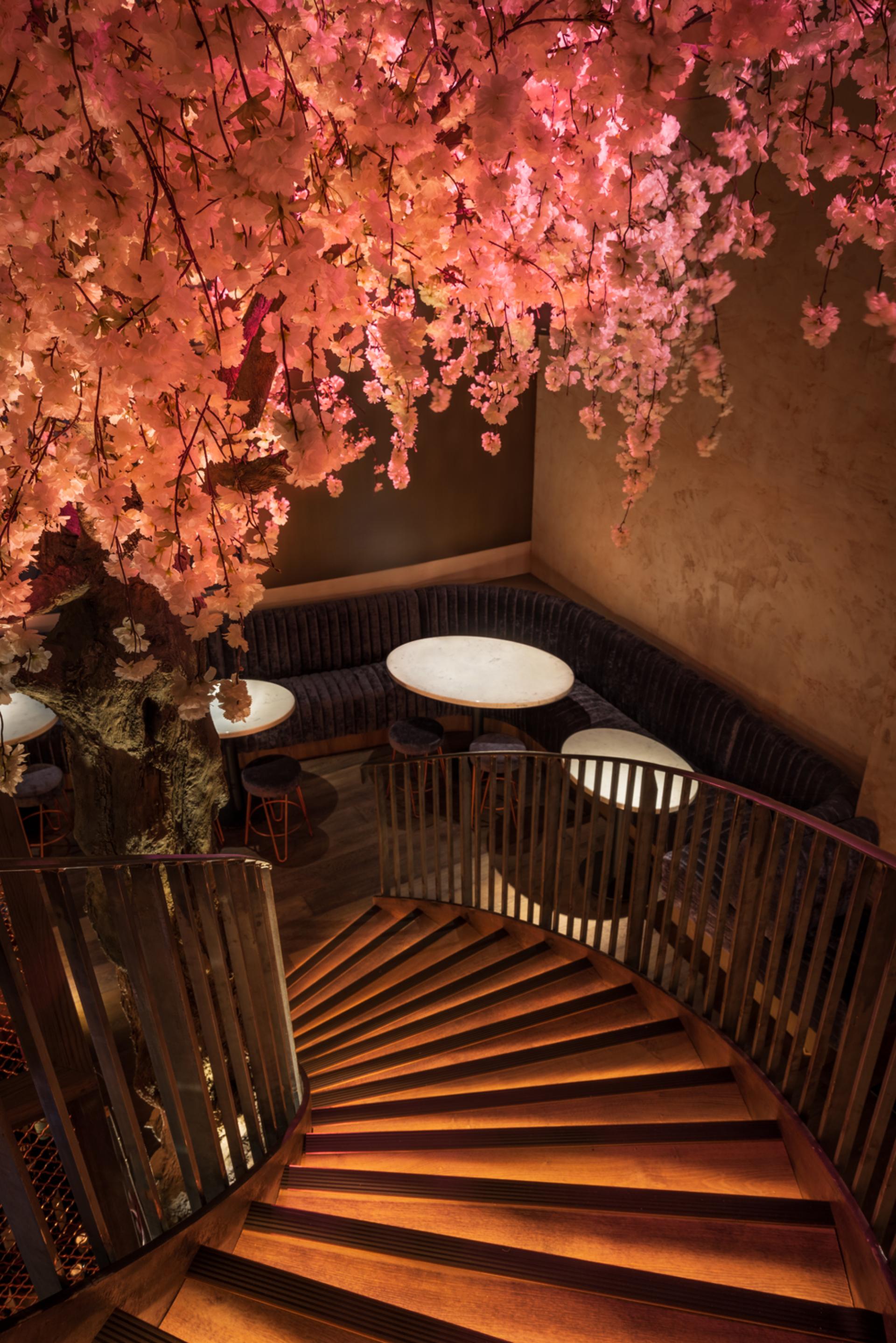 Stylish interior view of Andrew Wong's restaurant, featuring a spiral staircase and illuminated cherry blossom decor.