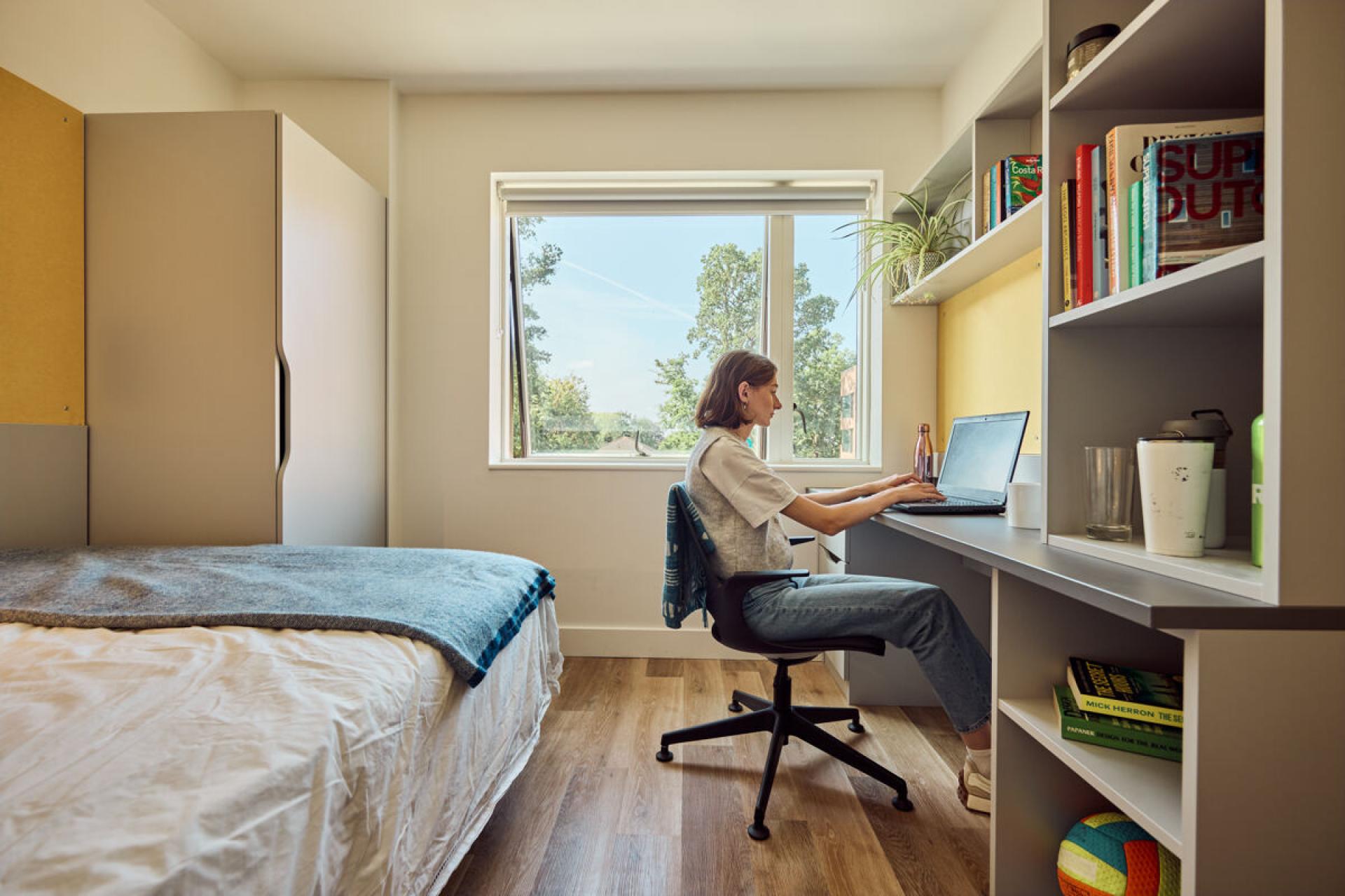 Modern student accommodation room at Oxford Brookes University, featuring a desk, laptop, and cozy furnishings.