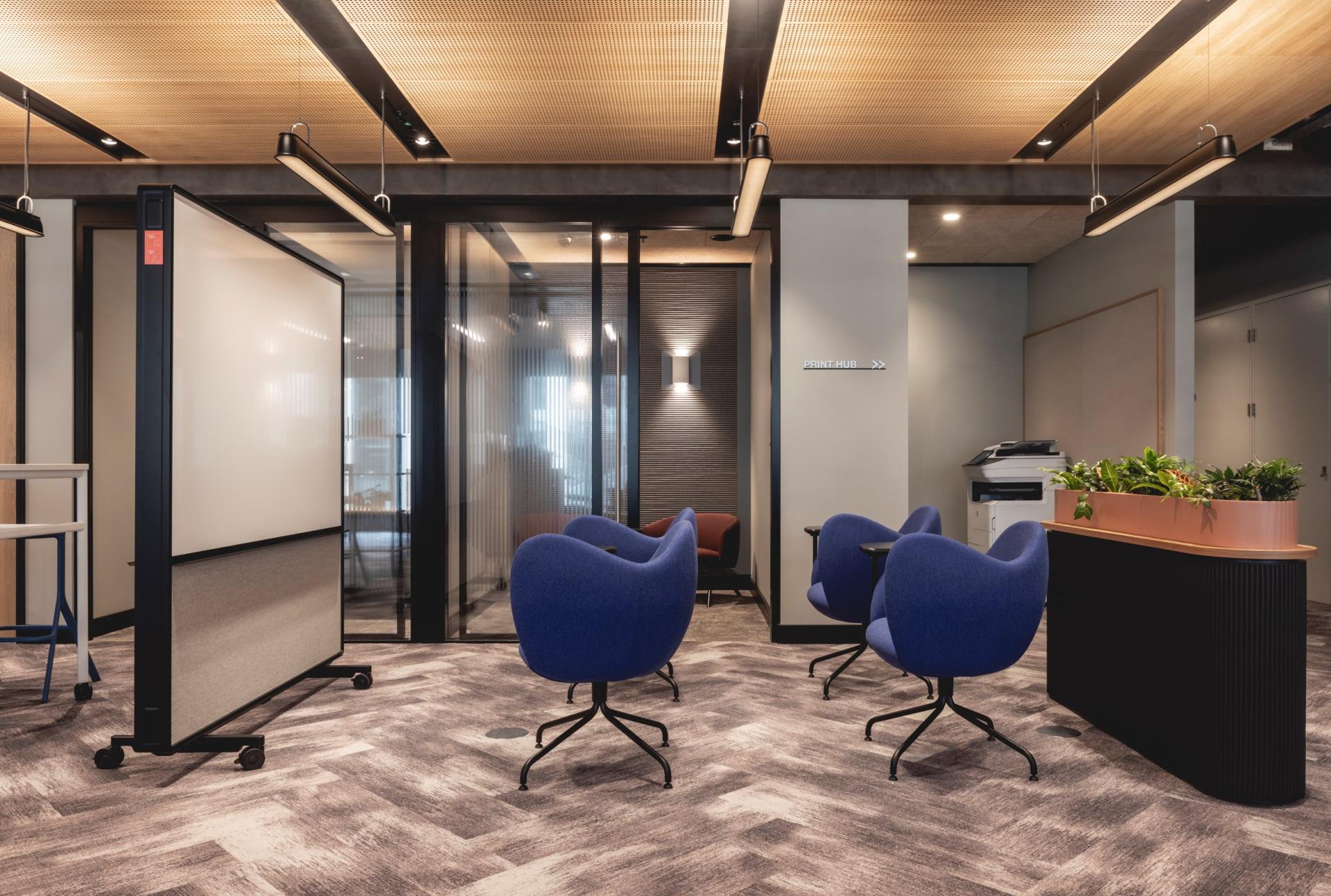 Modern workspace featuring Art Deco-inspired curves, blue chairs, and a calming ambiance created by Ekho Studio.