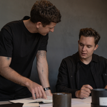 Two designers discuss ideas over sketches in a modern interior design studio, highlighting collaboration and creativity in Manchester.