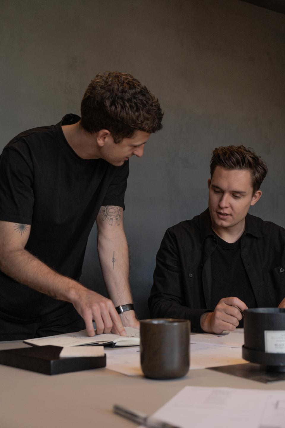 Two designers discuss ideas over sketches in a modern interior design studio, highlighting collaboration and creativity in Manchester.