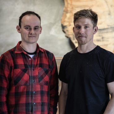 Louis Higgins and Ed Wilson of Takumi Woodwork pose in their workshop, showcasing craftsmanship and love for wood.