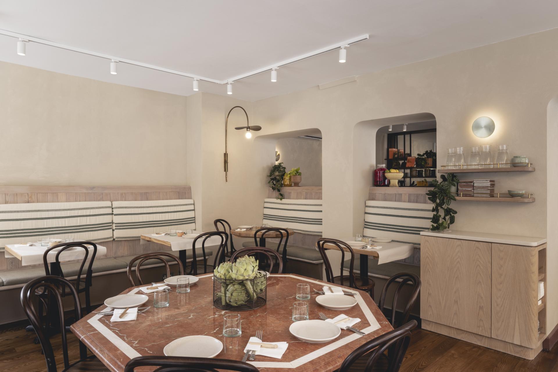 Modern interior of Honey & Co Bloomsbury featuring wooden furniture, striped seating, and a warm atmosphere.