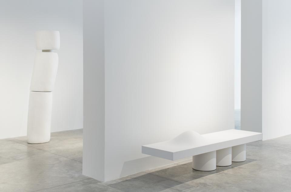 Minimalist sculptures and a sleek bench designed by Wendell Castle displayed in a contemporary gallery setting.