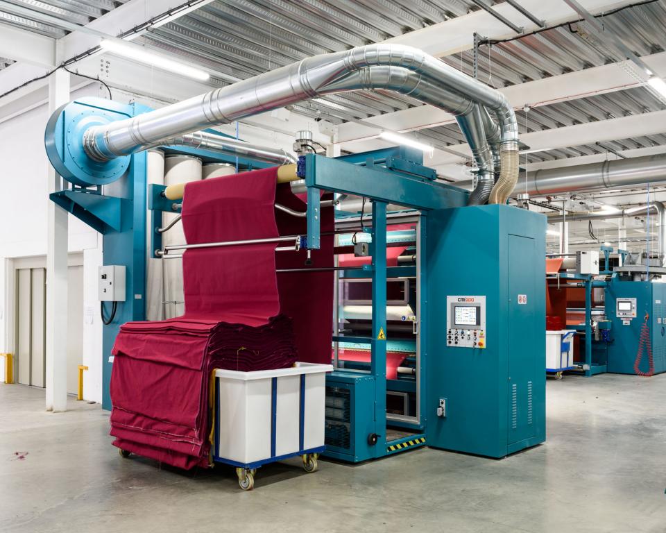 Upholstery textile production machinery at Kvadrat's facility, showcasing vibrant textile rolls ready for processing.