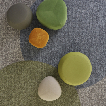 Colorful, irregularly shaped seating elements on a patterned floor, showcasing Tarkett DESSO's Orchard collection design.
