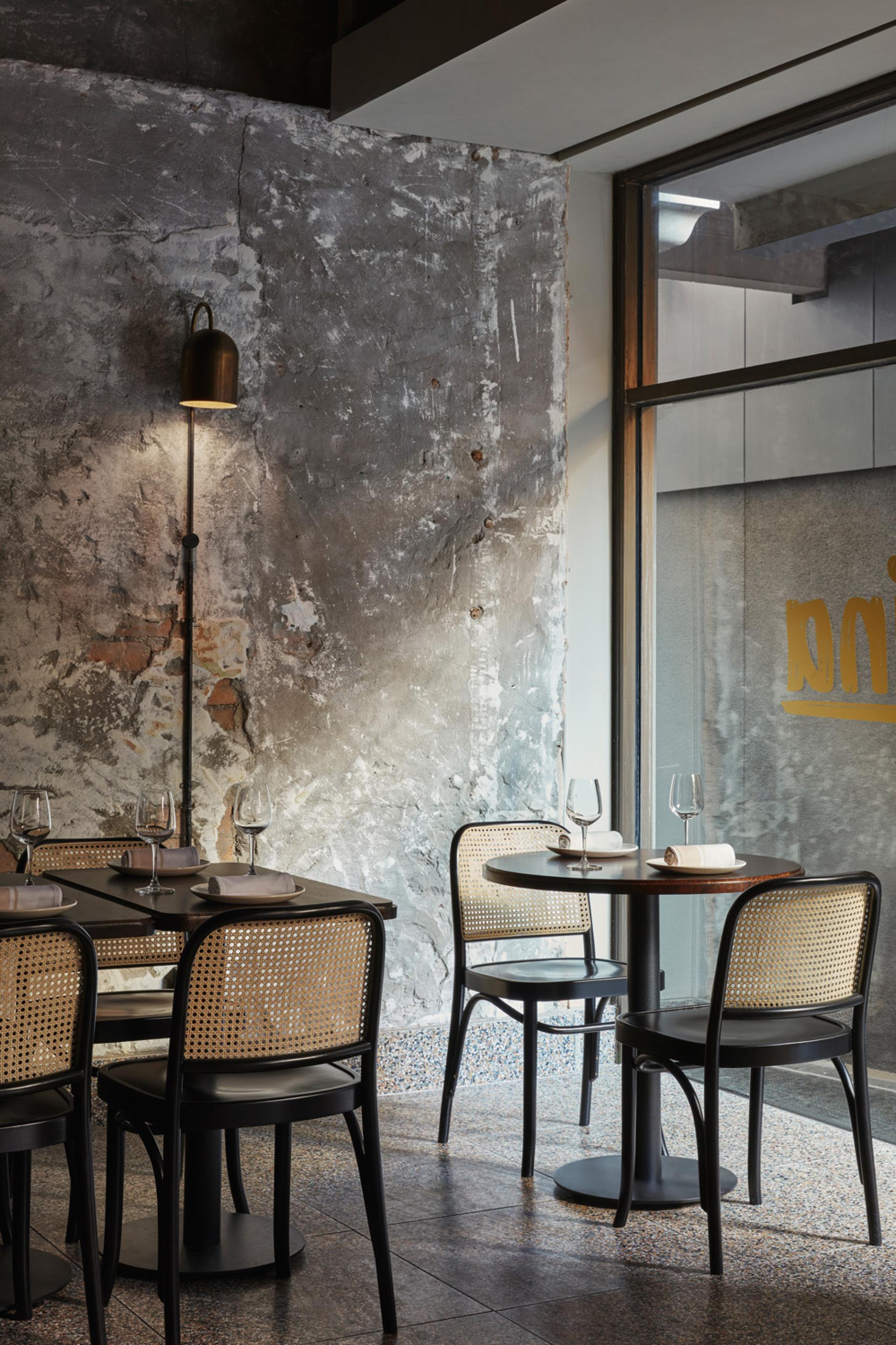Stylish interior of Pentolina restaurant, featuring modern tables, elegant chairs, and rustic textured walls reflecting Italian dining ambiance.
