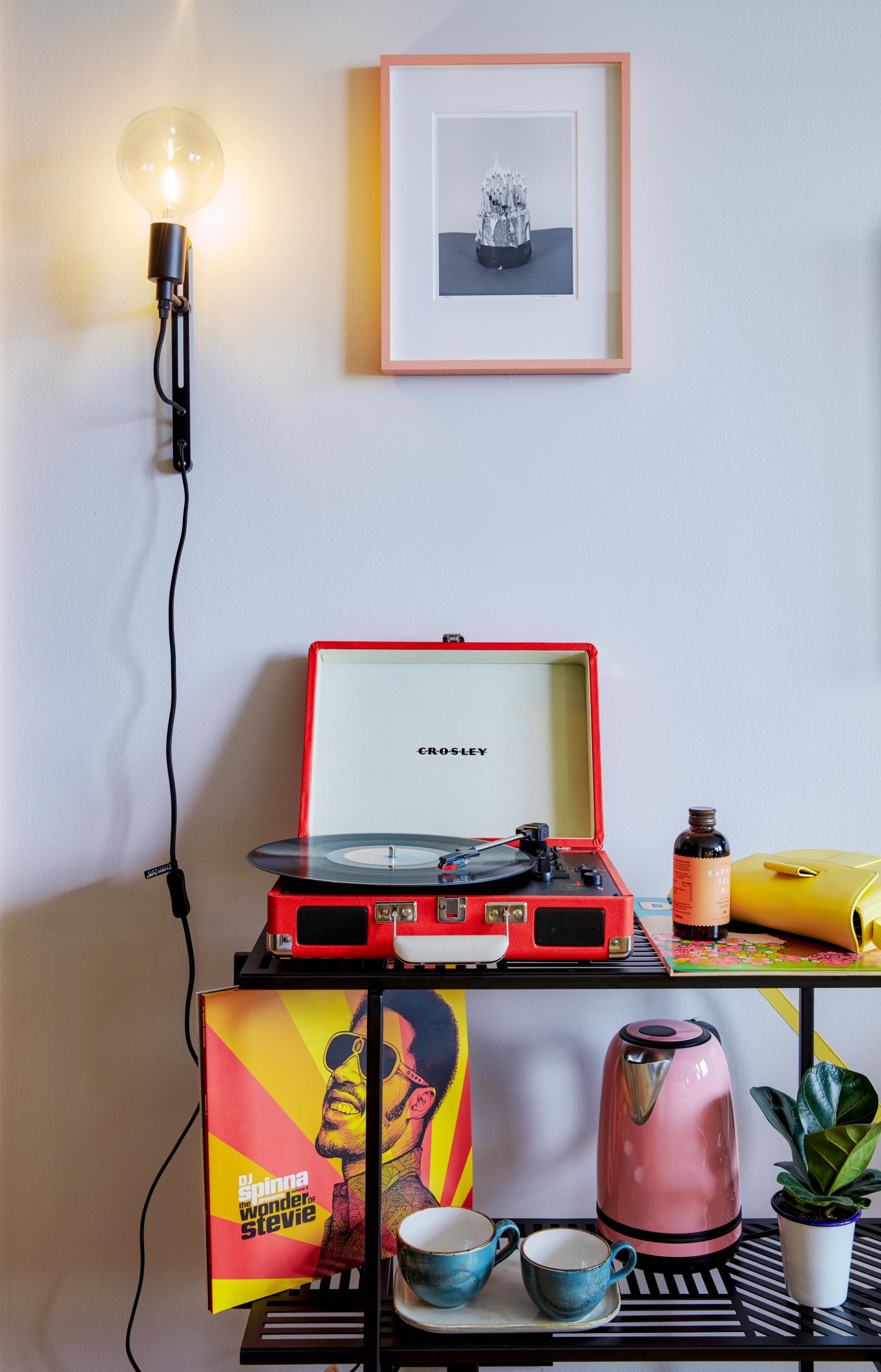 A vintage red record player, vibrant artwork, and stylish decor elements in a modern hotel room setting.