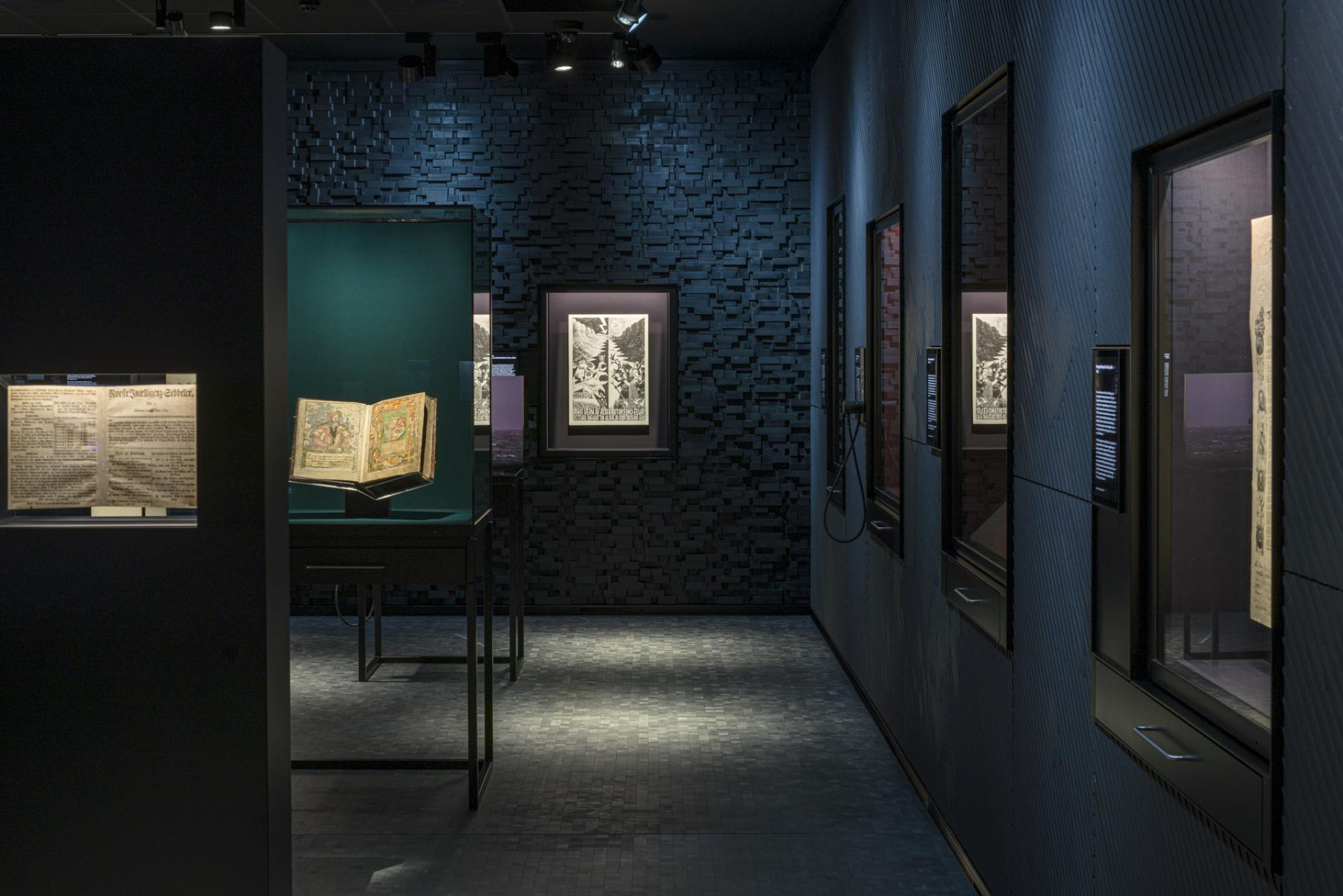 Exhibition space showcasing illuminated manuscripts and artworks, highlighting innovative architecture and theatre design by Nissen Richards Studio.