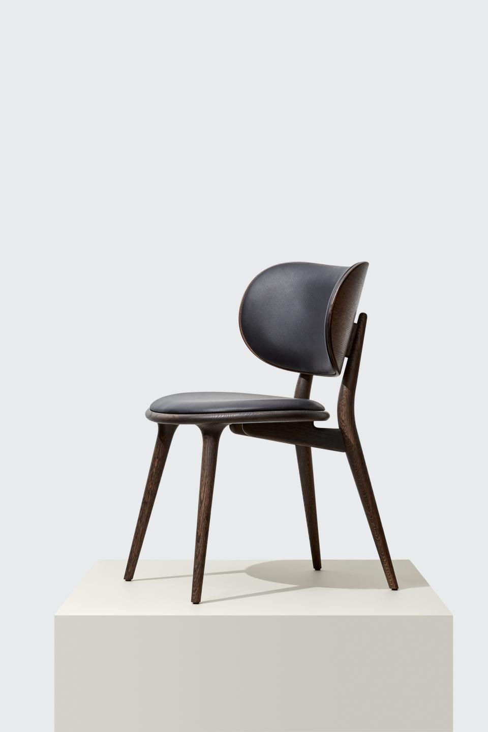 Stylish wooden chair with a black leather seat, showcasing Danish design by Mater at Salone del Mobile 2019.