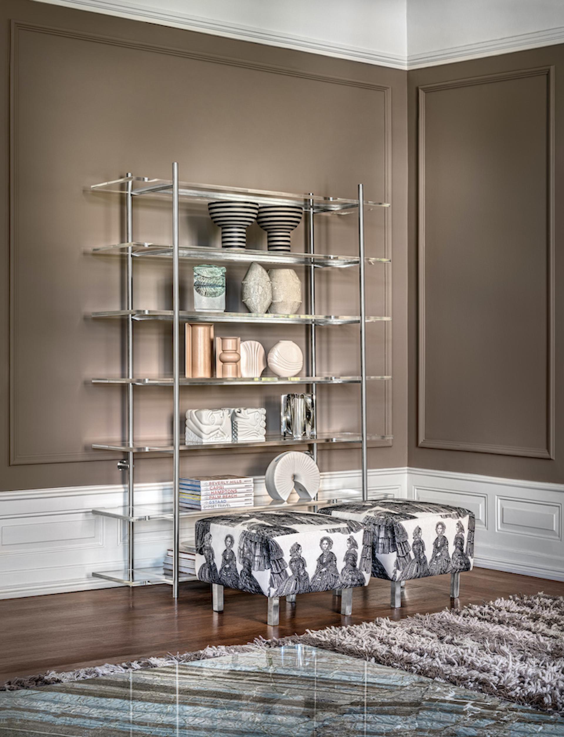 Modern luxury furniture display featuring sleek shelving, decorative vases, and upholstered stools designed by Cristina Jorge de Carvalho.