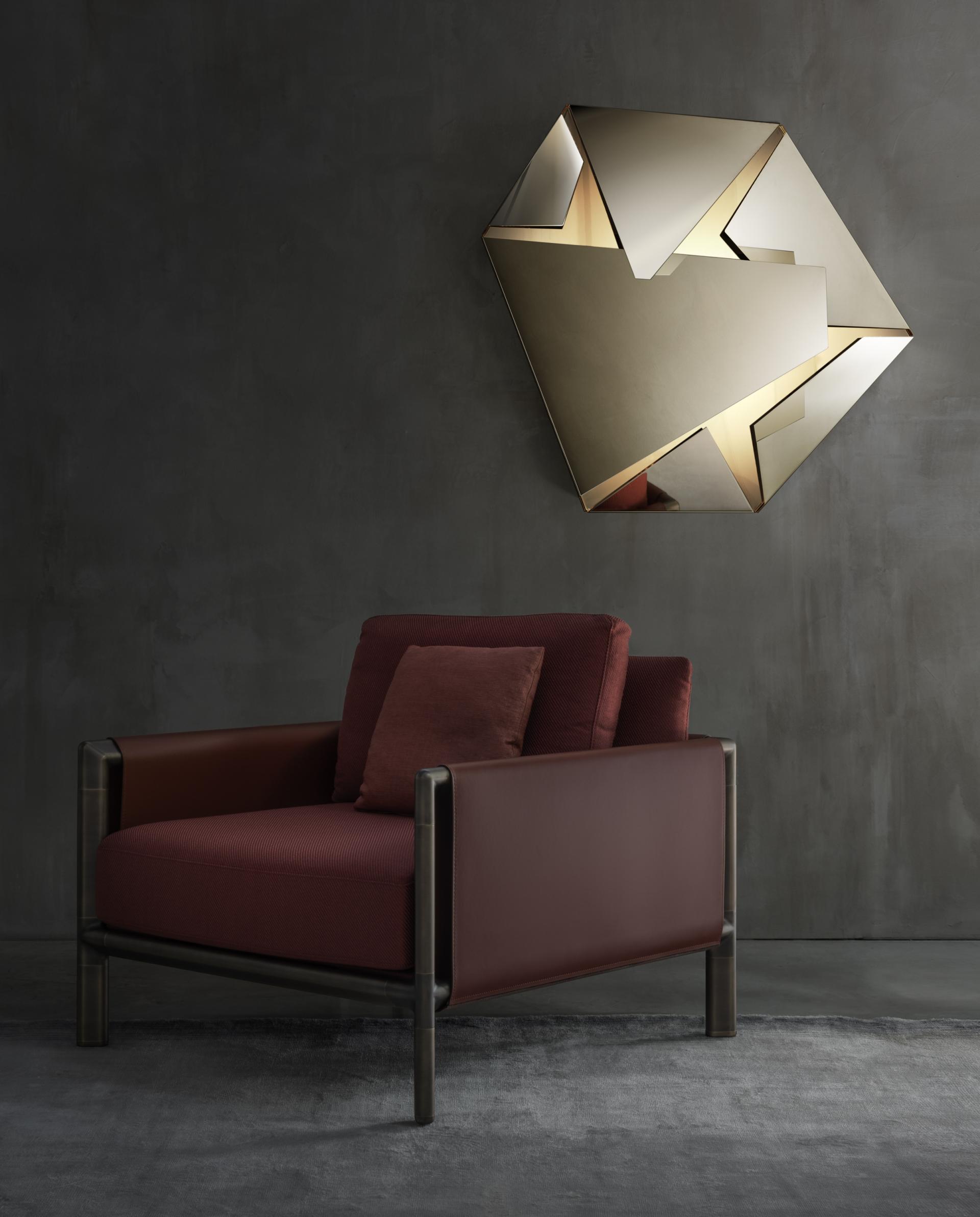 Elegant GHIDINI 1961 armchair with rich burgundy upholstery, paired with a modern brass geometric wall light.