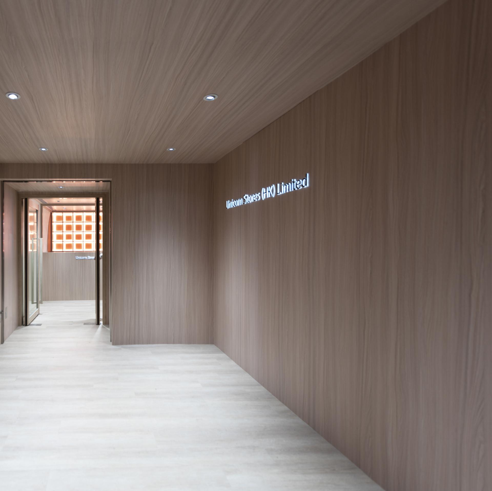 Modern interior of Unicorn Stores HQ featuring wooden walls and illuminated company signage, reflecting corporate heritage.