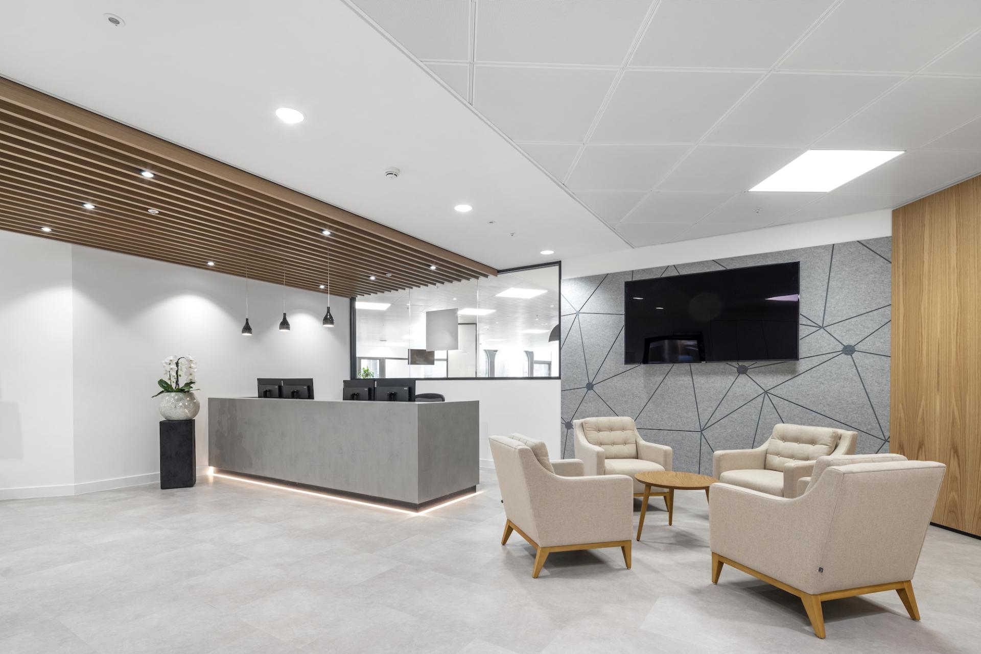 Modern office reception with a sleek desk, stylish seating, and a tech-inspired wall design, representing innovative workplace design.