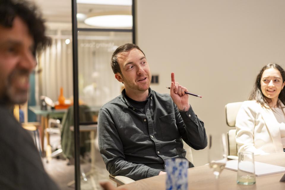 Group discussion on technology and sustainability in design, featuring engaged participants in a modern meeting space.