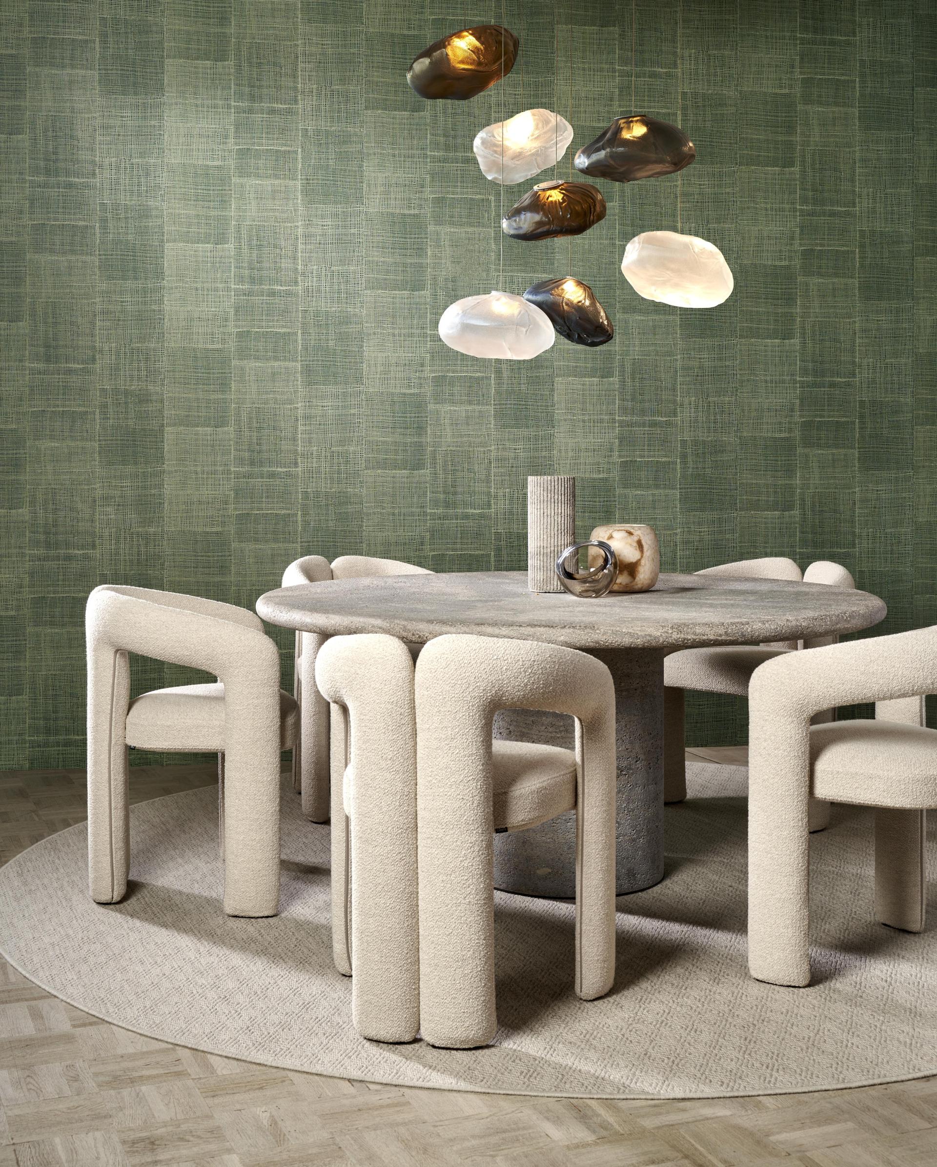 Modern dining area featuring abstract sculpture-inspired wallcovering, a textured round table, and unique upholstered chairs.