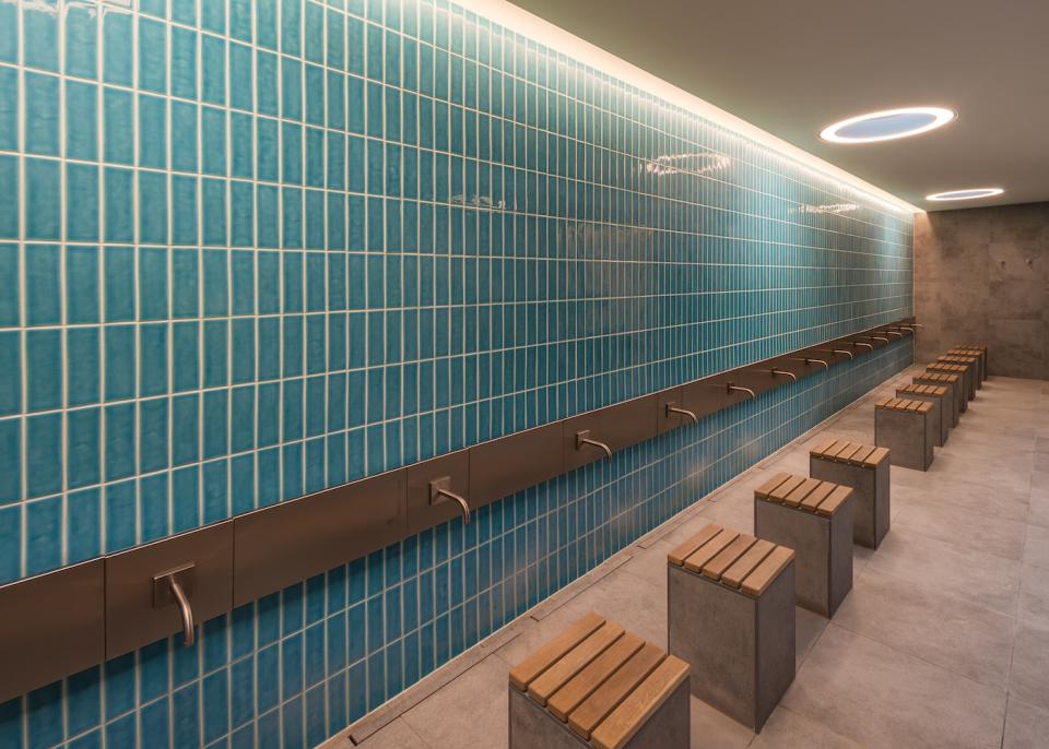 Modern wash area in Cambridge Central Mosque featuring turquoise tiled walls and minimalist seating, emphasizing sustainable design.