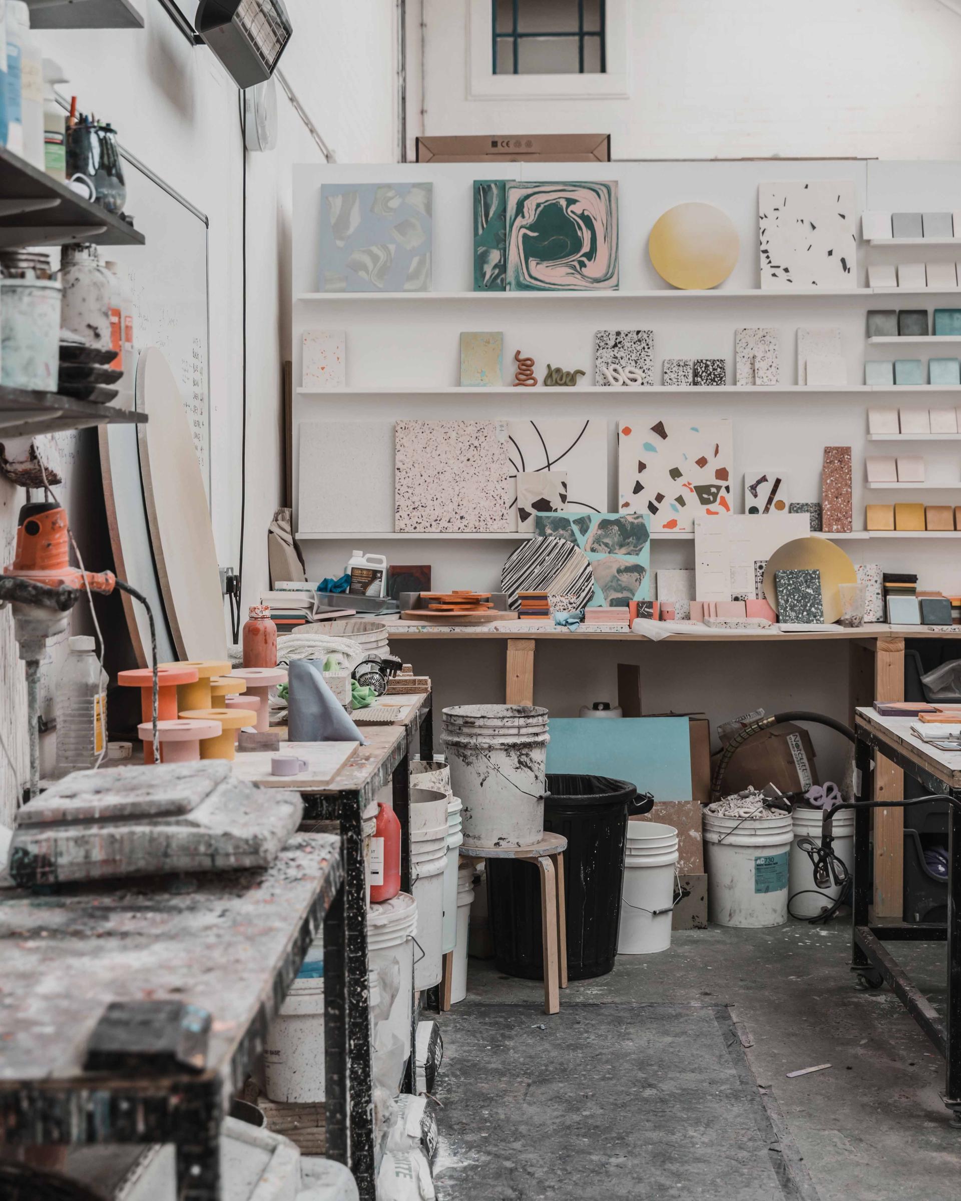 Art studio featuring colorful ebonite terrazzo samples, displays, and various materials for AJOTO's new desk rest designs.