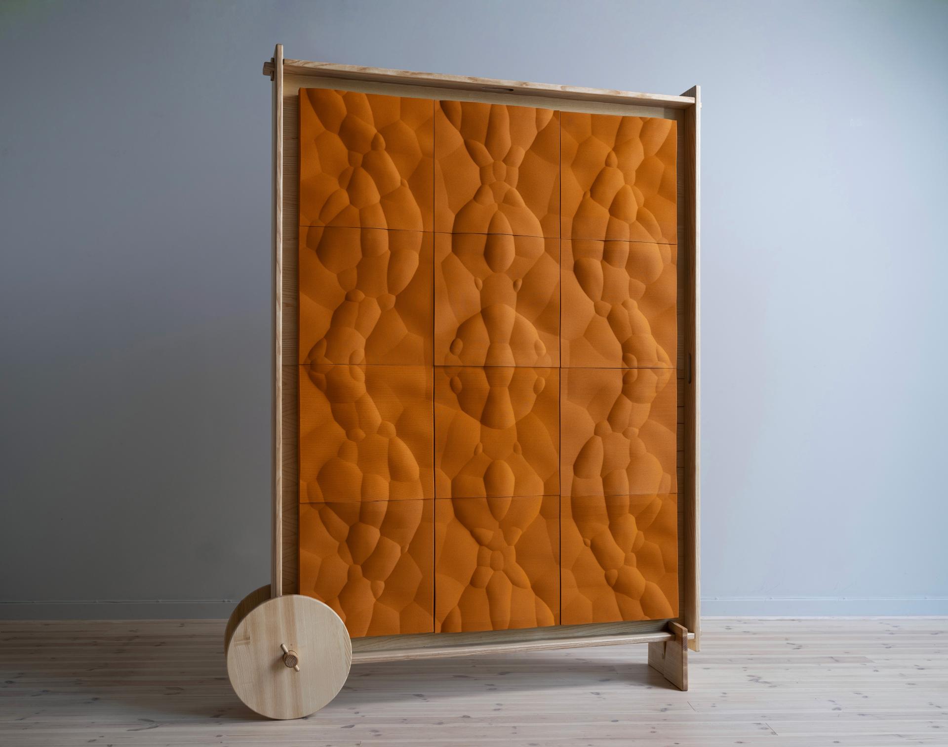 Sustainable wooden partition featuring textured orange panels, showcasing innovative biomaterial design for eco-friendly interiors.