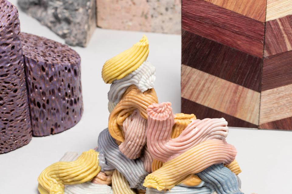 Colorful sculpture made of varied materials, surrounded by textured blocks, highlighting natural and man-made design elements.