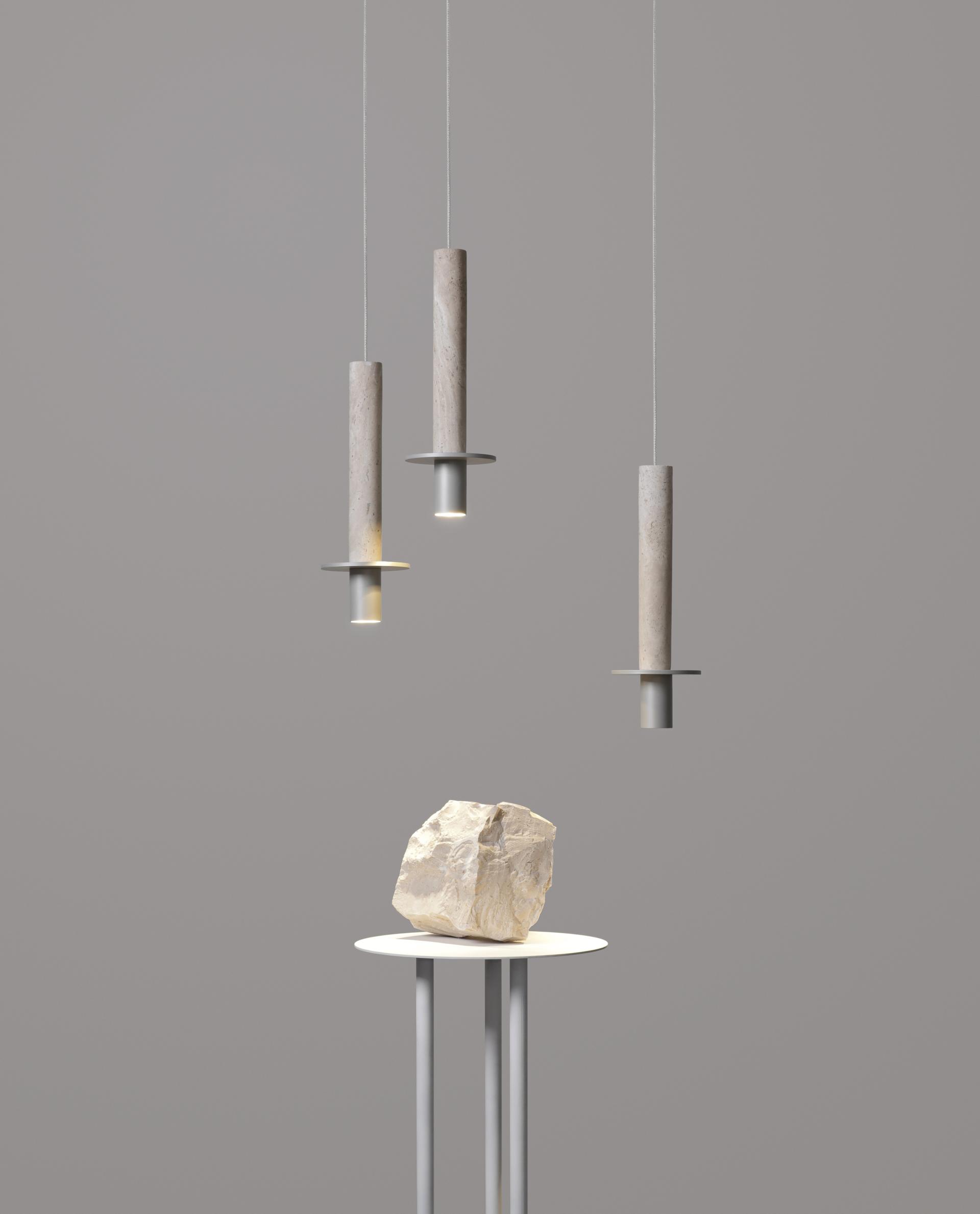 Three pendant lights in neutral tones above a sleek table sculpture, showcasing the Meta collection's new finishes.