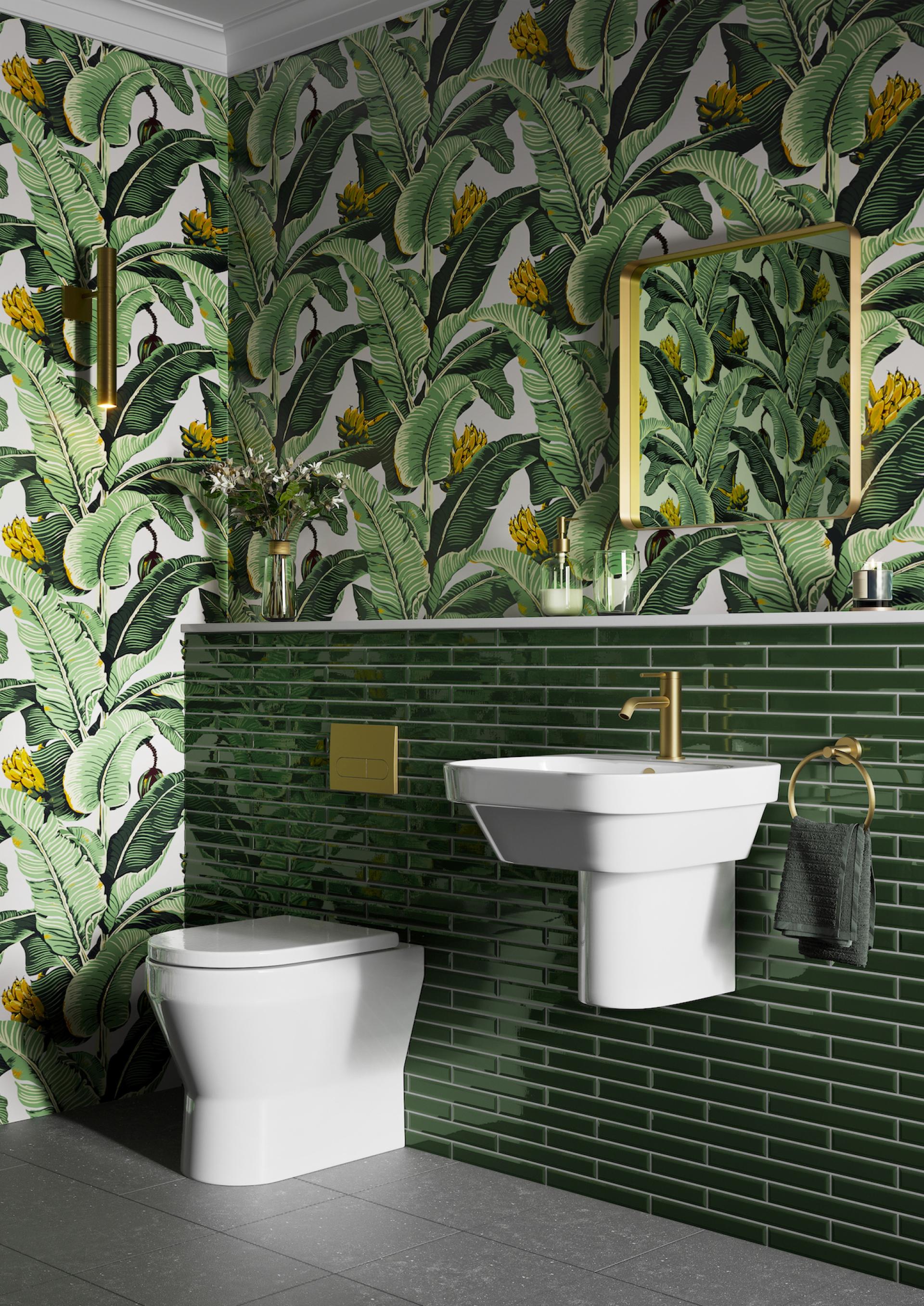 Stylish bathroom featuring botanical wallpaper, green tiled wall, gold fixtures, and modern white sink and toilet design.